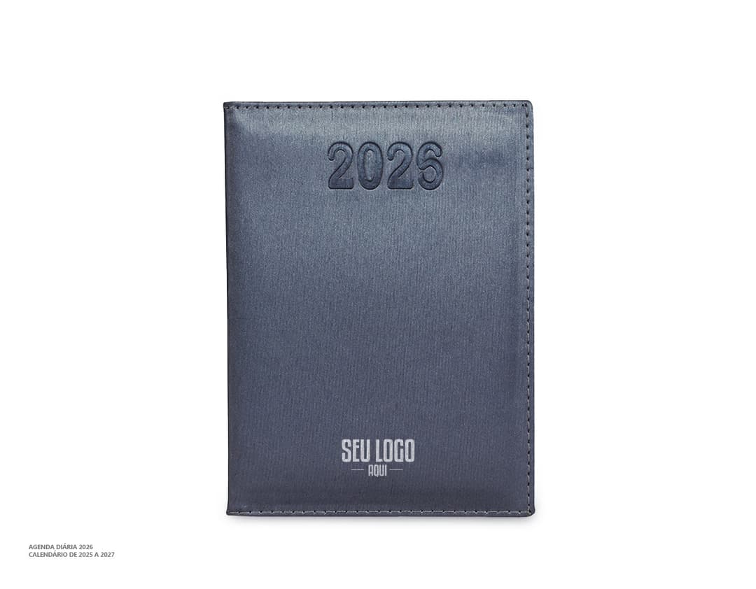Agenda Diária 2025 de capa preta com detalhes dourados e páginas em branco, sobre uma mesa de madeira com caneta ao lado.