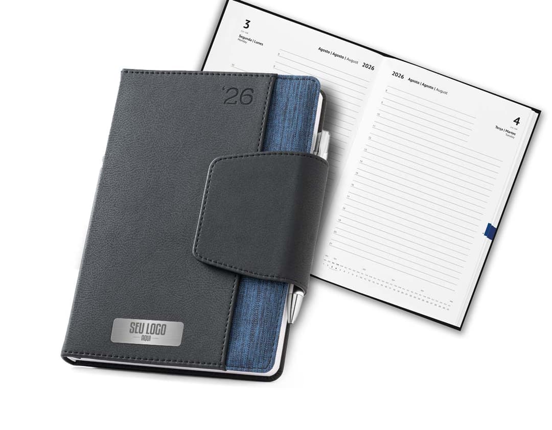 Agenda com fecho magnético em fundo rosa claro, contendo páginas em branco e caneta ao lado.