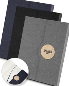 Caderno de anotações marrom com capa de couro vazia sobre uma mesa de escritório. O caderno está aberto exibindo páginas em branco e ao redor dele há um teclado de computador, um disquete, um laptop, um disco magnético, papel, uma pasta, um cartão e uma caneta. A imagem transmite uma sensação de negócios e tecnologia.
