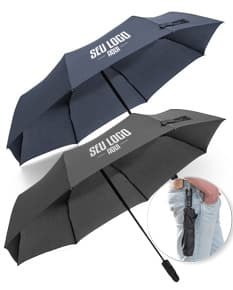 Guarda-chuva dobrável preto em formato de capelo de formatura, simbolizando sucesso e educação. O objeto 3D está aberto e vazio, sendo segurado por uma mão masculina. A imagem representa conhecimento, celebração e conquista acadêmica.