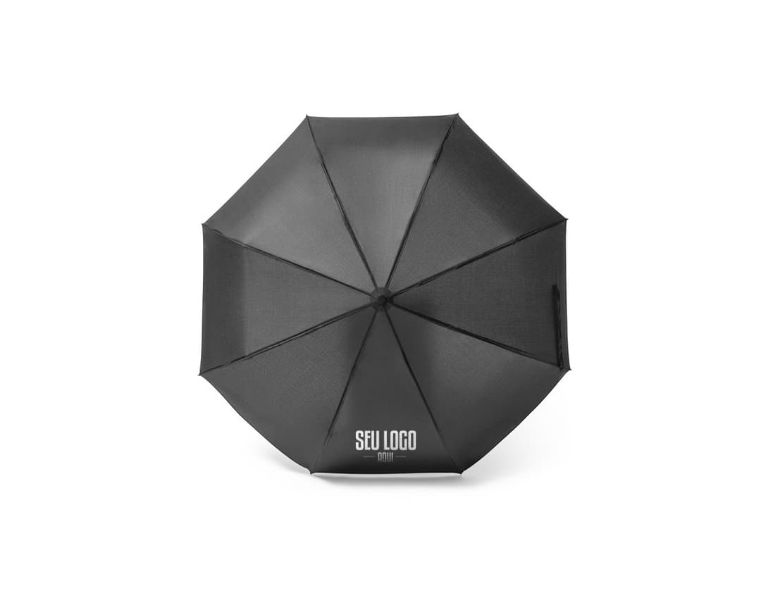Guarda-chuva dobrável preto em formato de capelo de formatura, simbolizando sucesso e educação. O objeto 3D está aberto e vazio, sendo segurado por uma mão masculina. A imagem representa conhecimento, celebração e conquista acadêmica.
