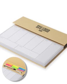Bloco de anotações com planejamento aberto em uma mesa de escritório. No bloco, é possível ver páginas decoradas e datas planejadas. Além disso, há canetas e clips ao redor do bloco.