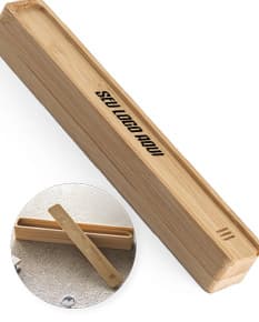 Estojo em bambu com fecho dourado, contendo lápis, caneta, régua e apontador.