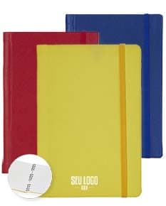 Caderneta Emborrachada com Wire-o em amarelo, design de quadro adesivo vazio em um notebook aberto, com papel em branco e um envelope de papel à direita, sobre fundo liso e limpo.