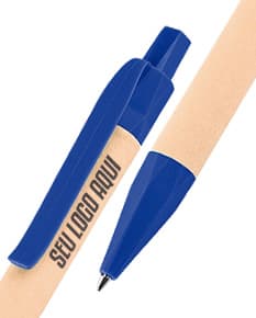  Caneta ecológica de papel com tampa e clip em metal, na cor azul com detalhes em verde. Ao fundo, folhas verdes e uma xícara de café.