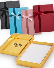 Caixa de presente na cor vermelha, com laço dourado e pequenos detalhes brilhantes.