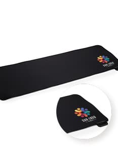 Desk Pad Microfibra com LED em formato retangular, na cor preta, com iluminação LED na parte inferior. O produto está sobre uma mesa de madeira, ao lado de um notebook e uma caneca de café.