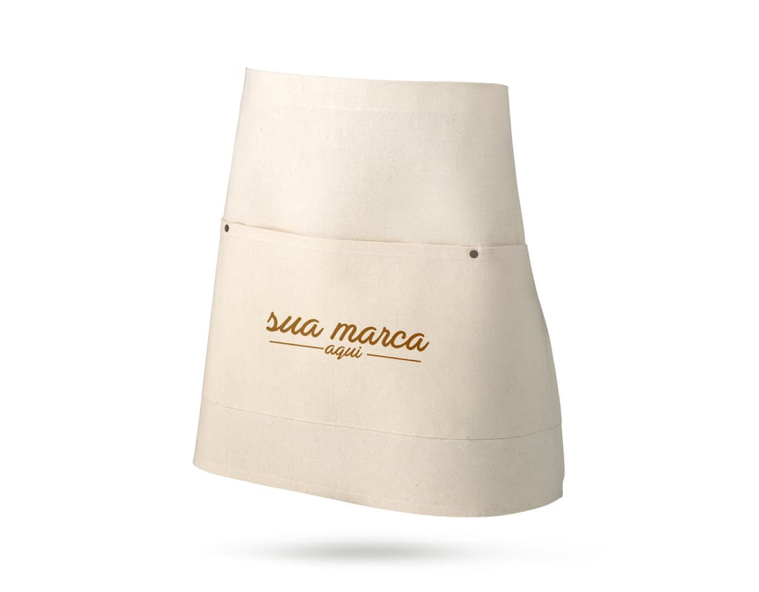 A imagem mostra um avental multiusos em um ambiente de cozinha. O avental é de cor amarela, tem um design vintage e está limpo e bem cuidado. À sua volta, aparecem alguns objetos como uma garrafa de perfume, comida, uma sacola, uma bandeja e um saco de pano. A cena transmite uma sensação de celebração e o avental parece estar pronto para ser usado.